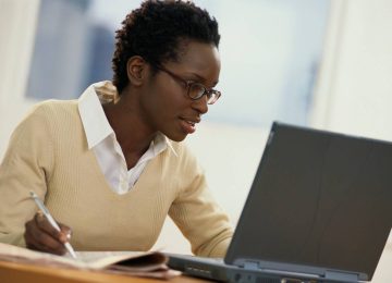 Photo of a usiu online student studying on a tablet in a café